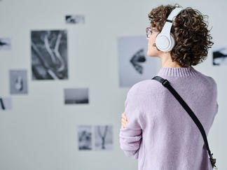 Museum visitor viewing an exhibit with an audio guide.